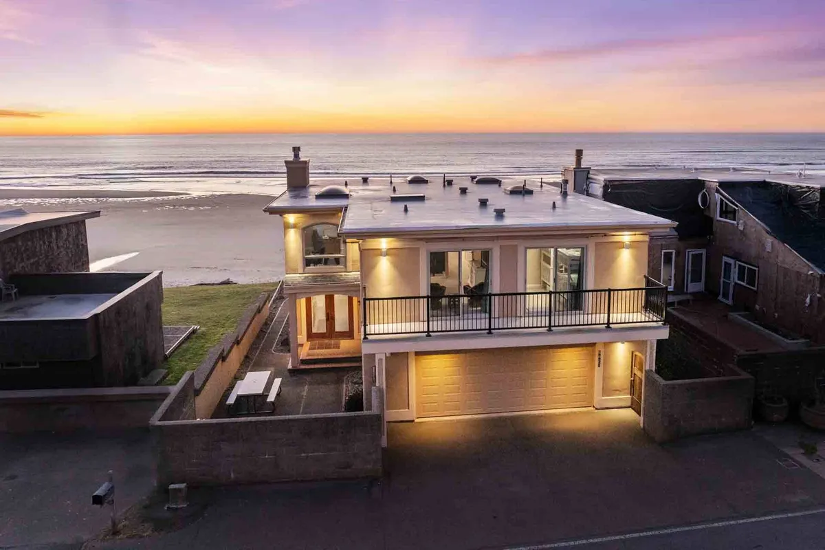 An exterior view showcasing the ocean at sunset, the balcony, and a relaxing outdoor setting perfect for unwinding. The scene evokes tranquility, with the sun dipping below the horizon, inviting guests to imagine themselves enjoying the coastal atmosphere from a private vantage point.